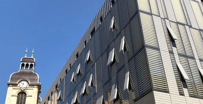 Façade contemporaine à trame verticale au pied d’un clocher ancien, projet Hôtel-Dieu